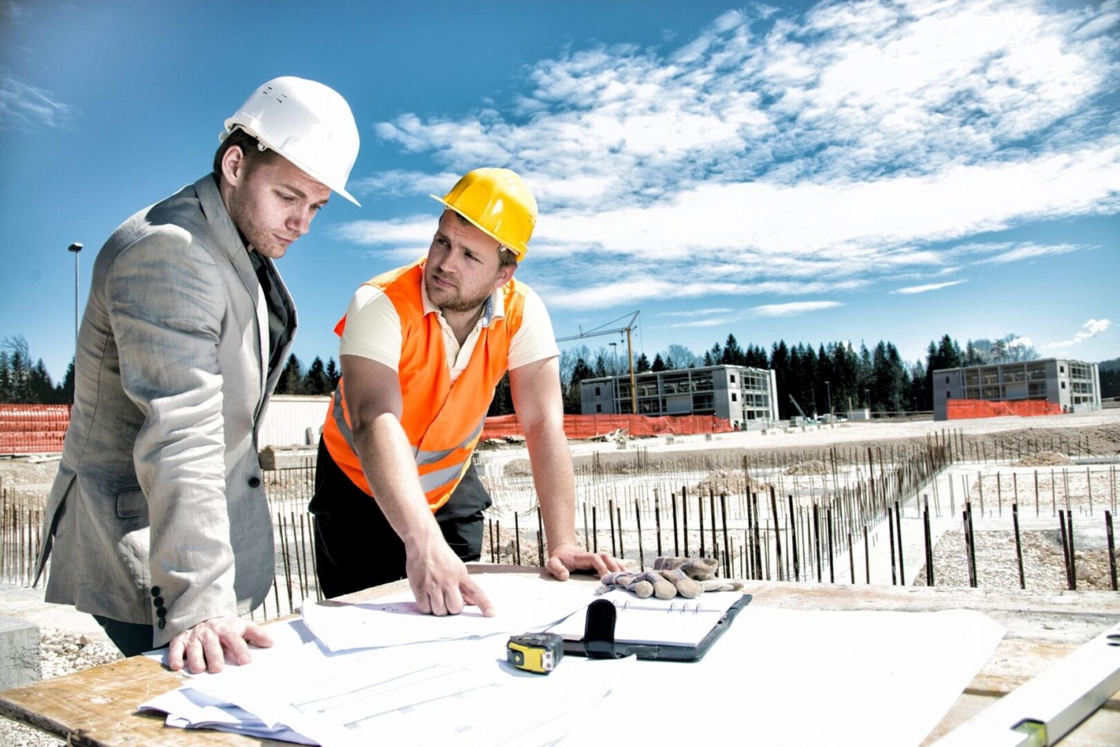 Two men in hard hats looking at plans on a construction site.